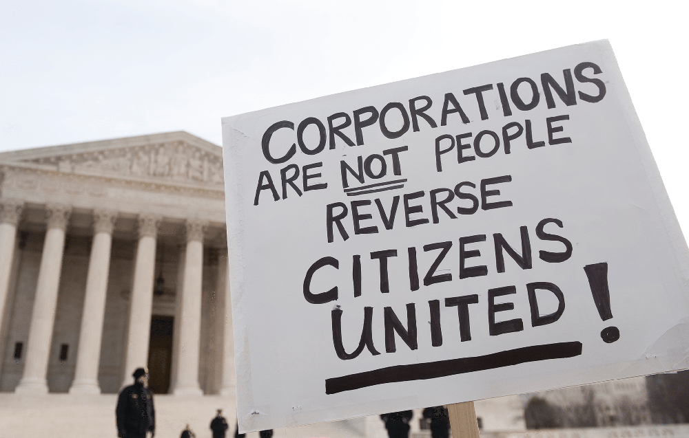 Protest sign in front of U.S. Congress that says 'Corporations are NOT people. Reverse Citizens United.'